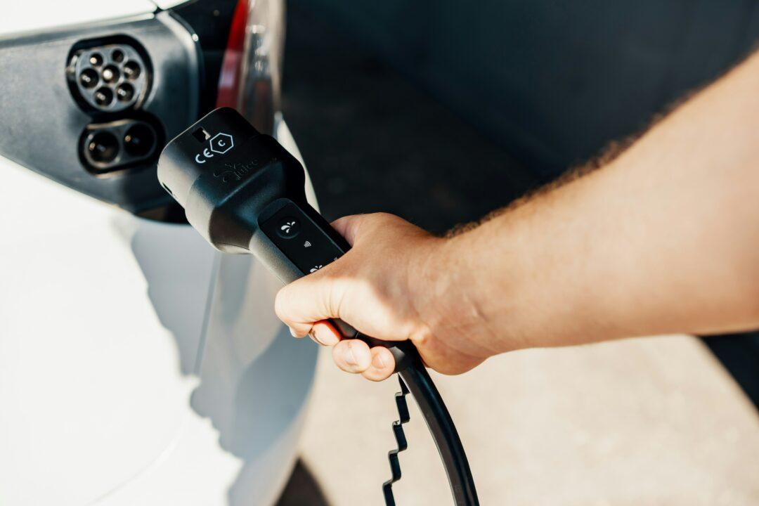 Ein Mensch hält ein Ladekabel für sein Elektroauto in der Hand.