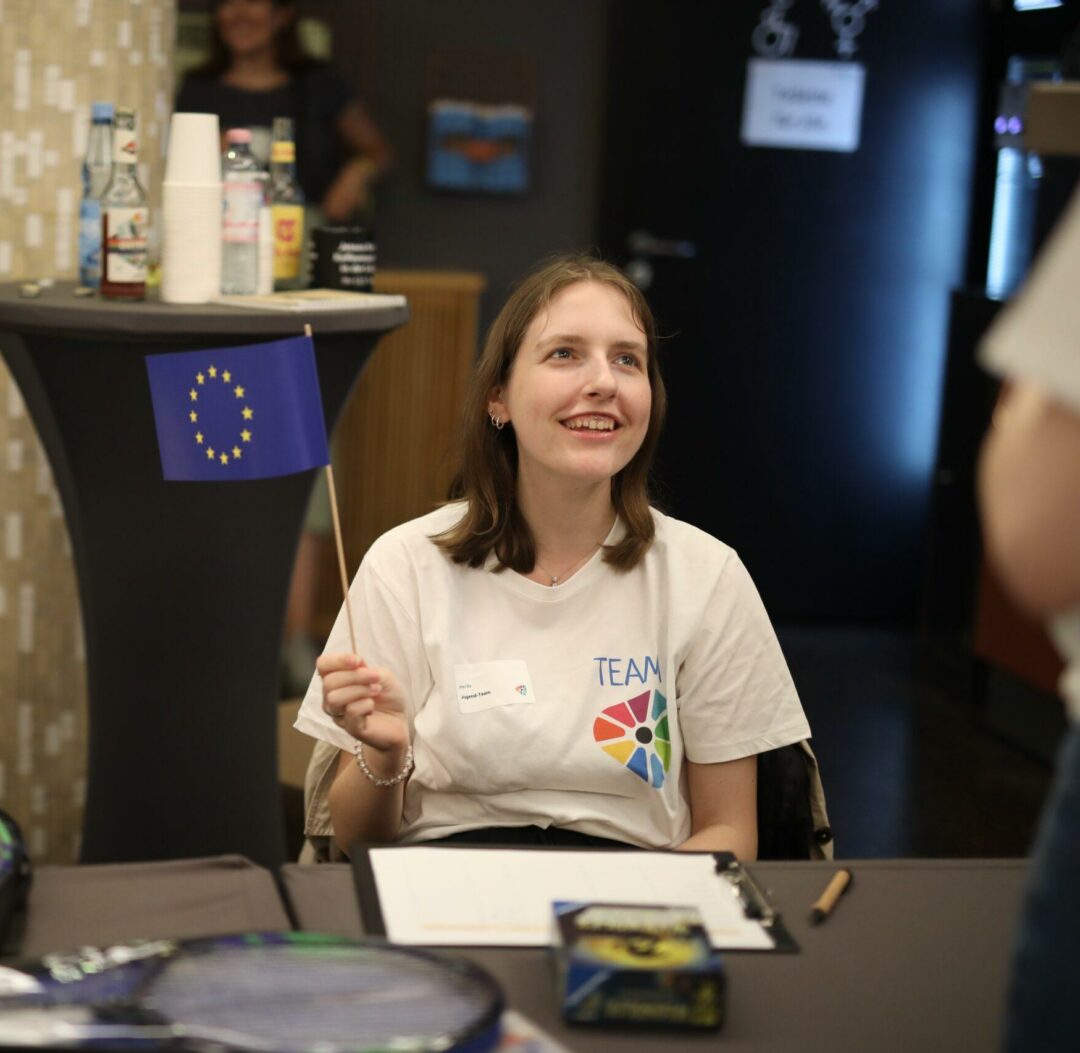 Eine junge Frau hält eine kleine Europa-Flagge in der Hand.